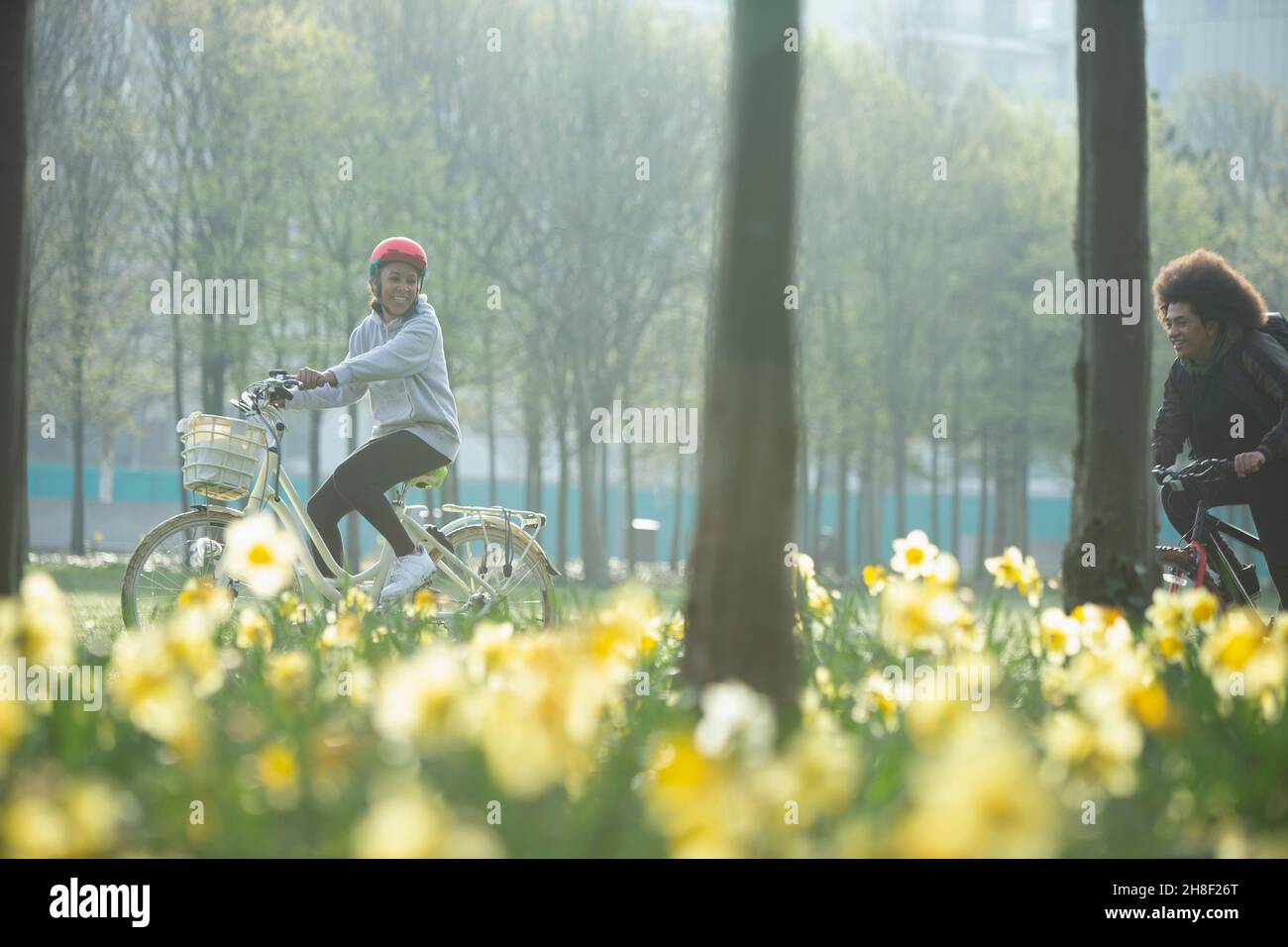 Happy teen friends riding bicycles in sunny spring park Stock Photo