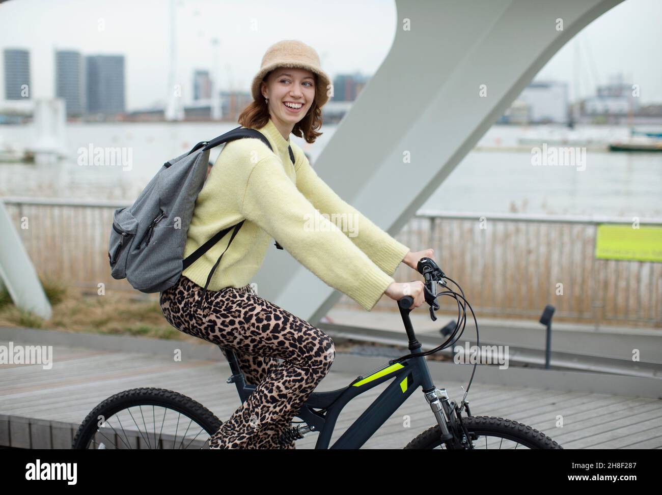 Portrait stylish young woman riding bicycle in city Stock Photo