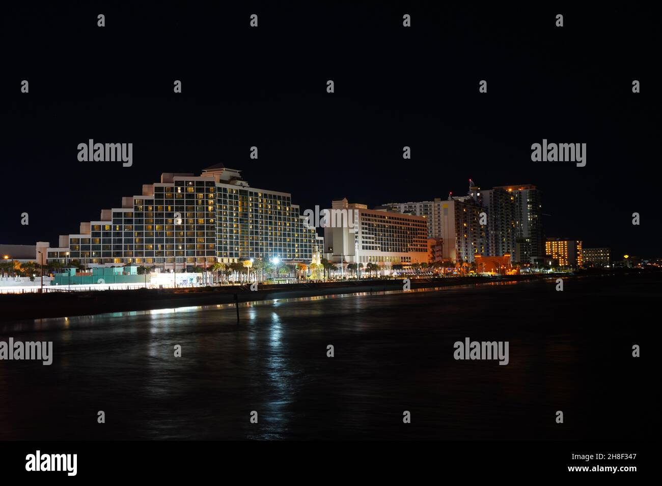 Night skyline of Daytona Beach, Florida, photographed from the fishing pier. Long exposure showing hotels, beach and waves. Stock Photo