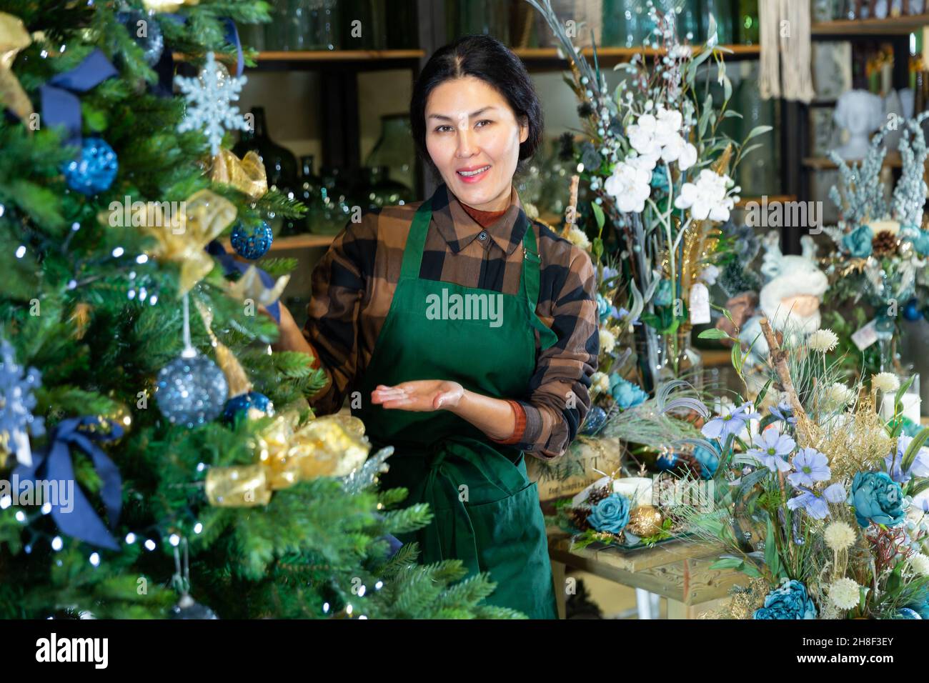 Woman salesman decorates christmas tree in flower shop Stock Photo Alamy