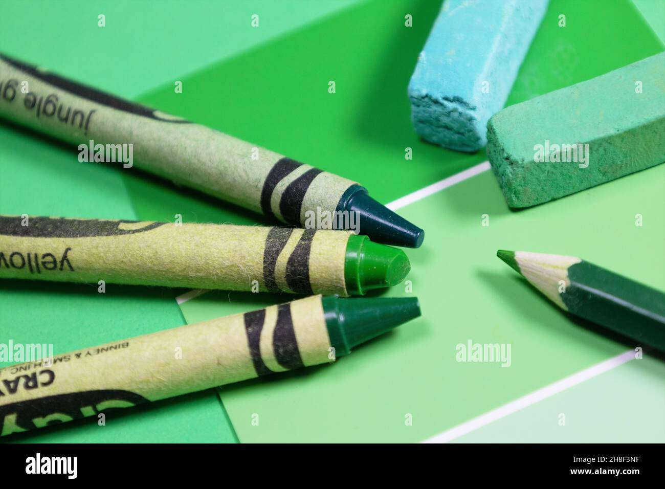 A paint swatch, crayons, pastels, and colored pencil, all representing