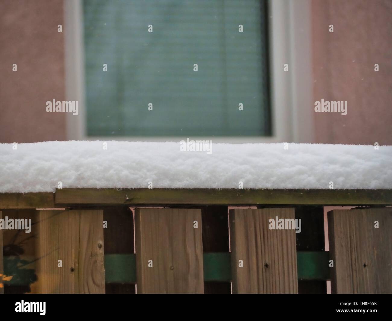 Close-up shot of a snow-capped fence with a background of a house ...