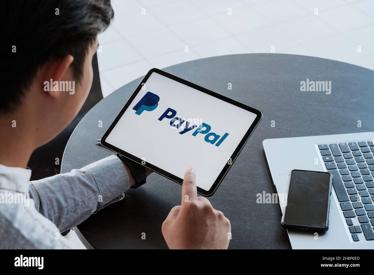 CHIANG MAI, THAILAND - NOV 28, 2021: Man holding a iPad with service PayPal on the screen Stock Photo