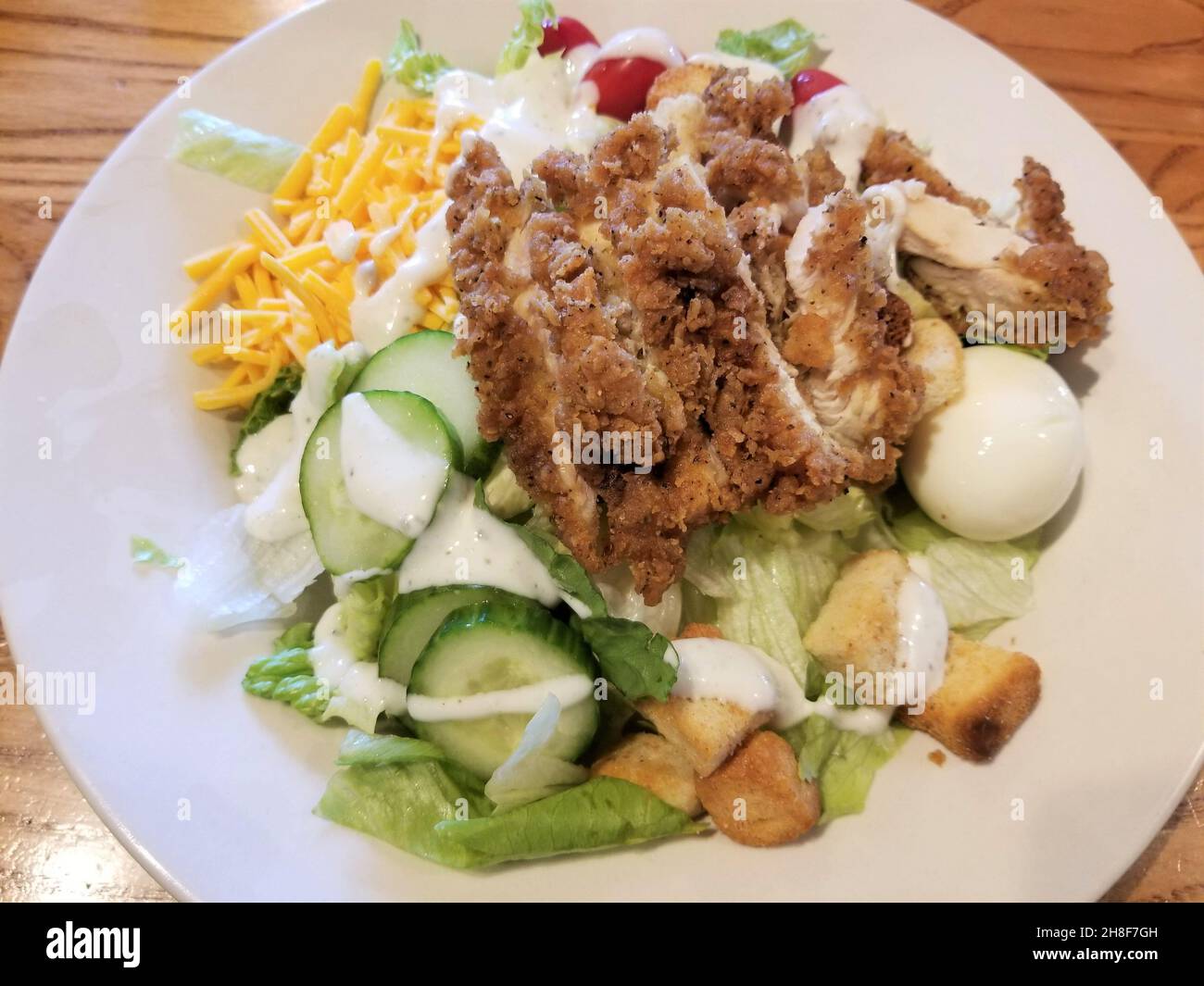 Homestyle fried chicken on top of a salad with lettuce, cucumbers