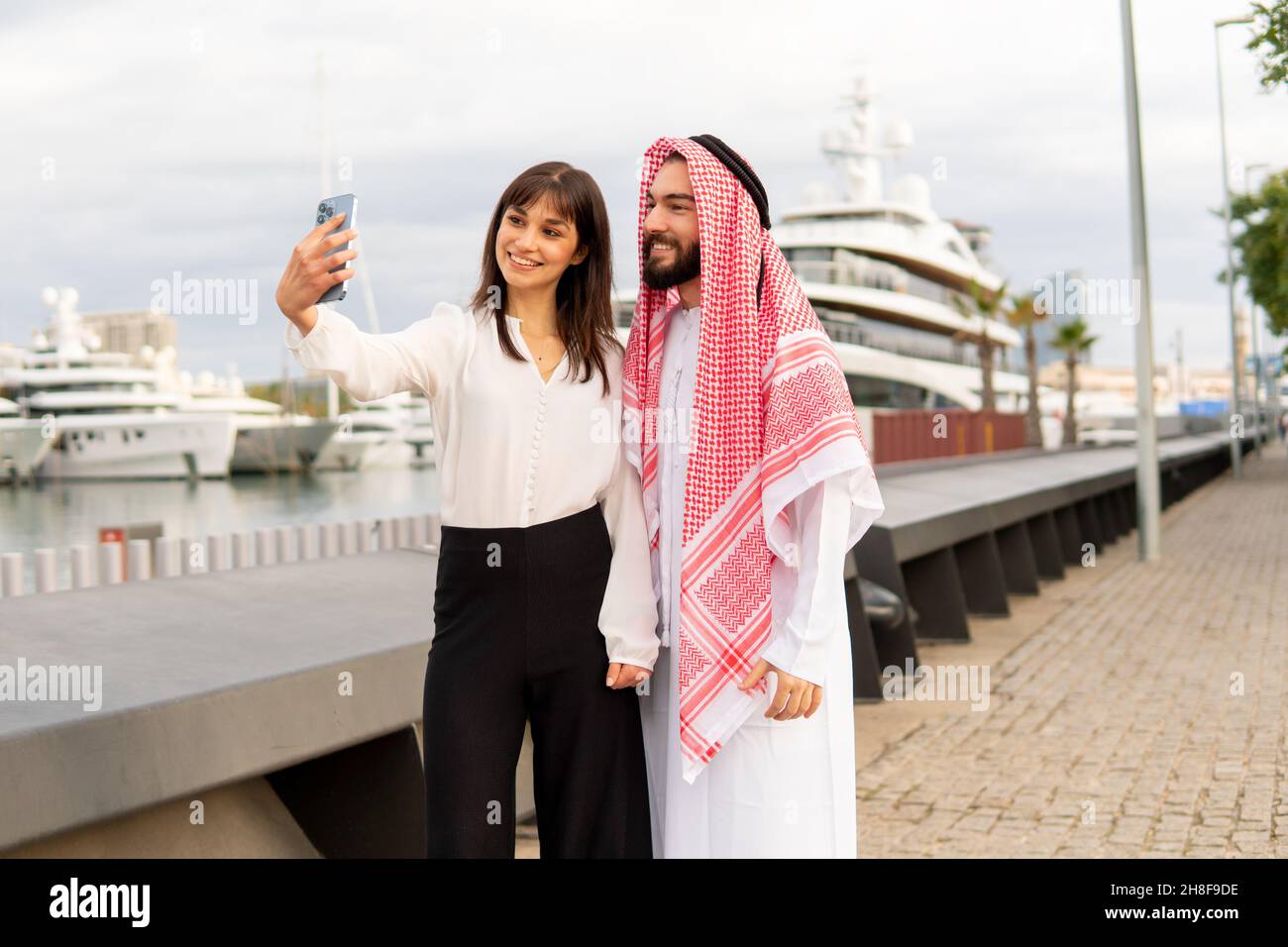 Female manager in formal wear smiling and taking selfie with Arab male client during meeting on embankment Stock Photo