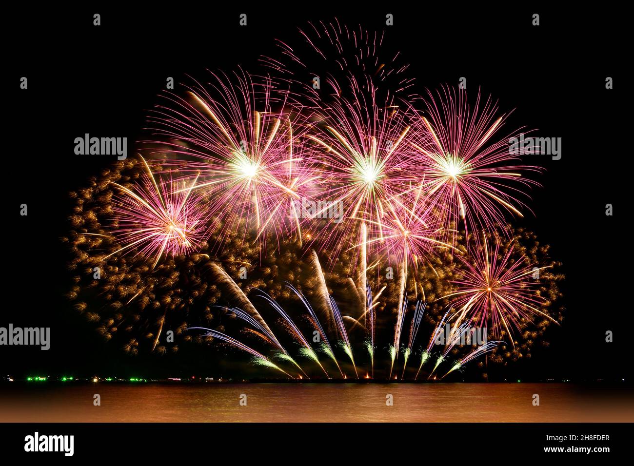 Firework celebration from the sea shore. Colorful fireworks celebration and the night sky background. Stock Photo