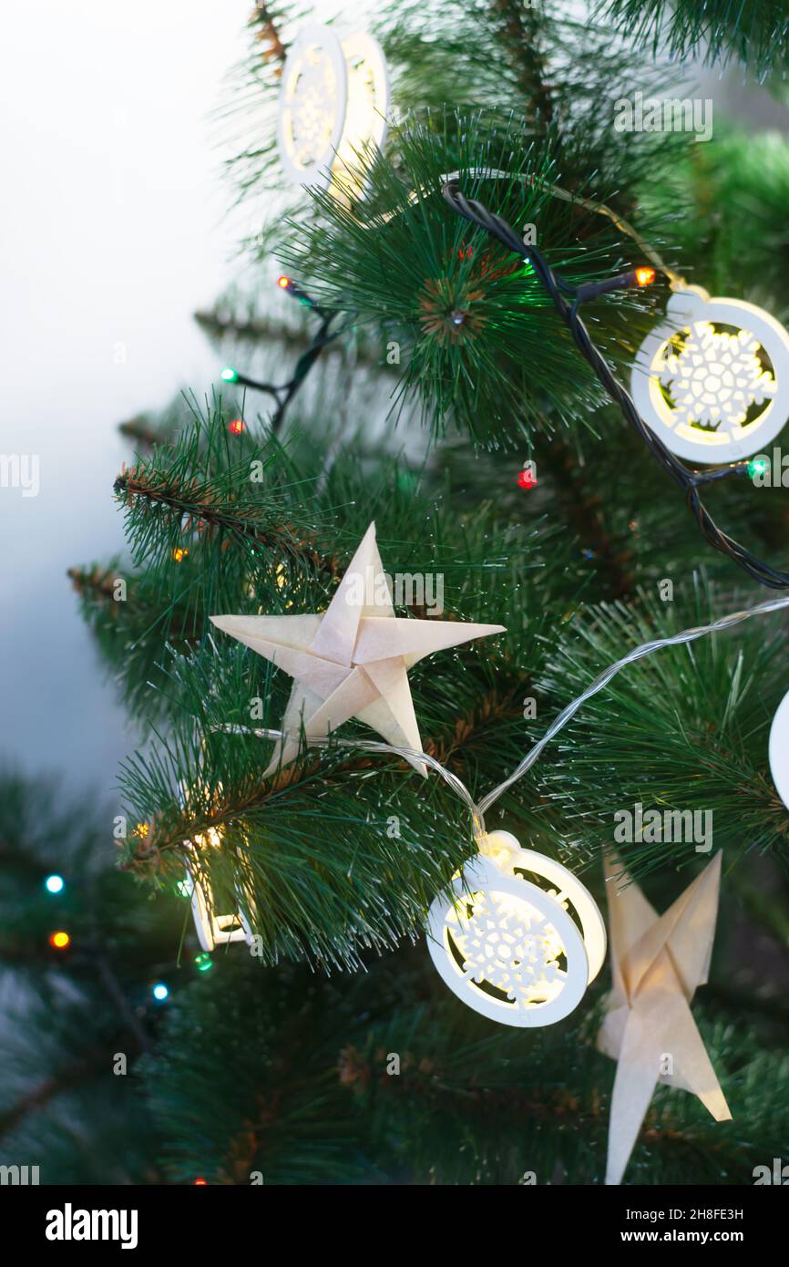 Origami stars from craft paper on an artificial Christmas tree with festive  lights. Alternative eco friendly Christmas tree decoration concept. DIY. V  Stock Photo - Alamy