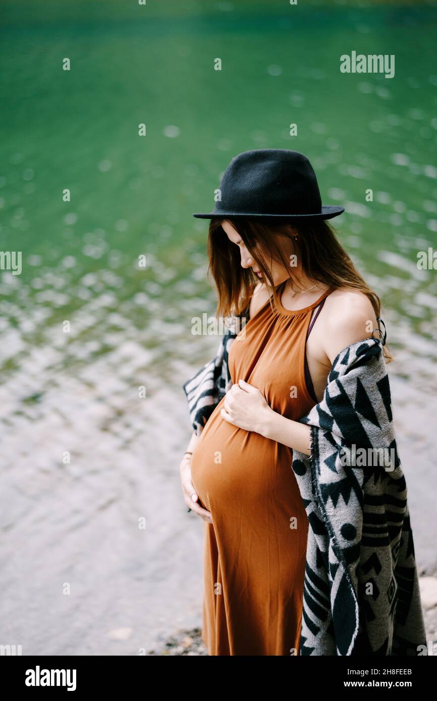 Pregnant woman hugs her belly by the lake Stock Photo - Alamy