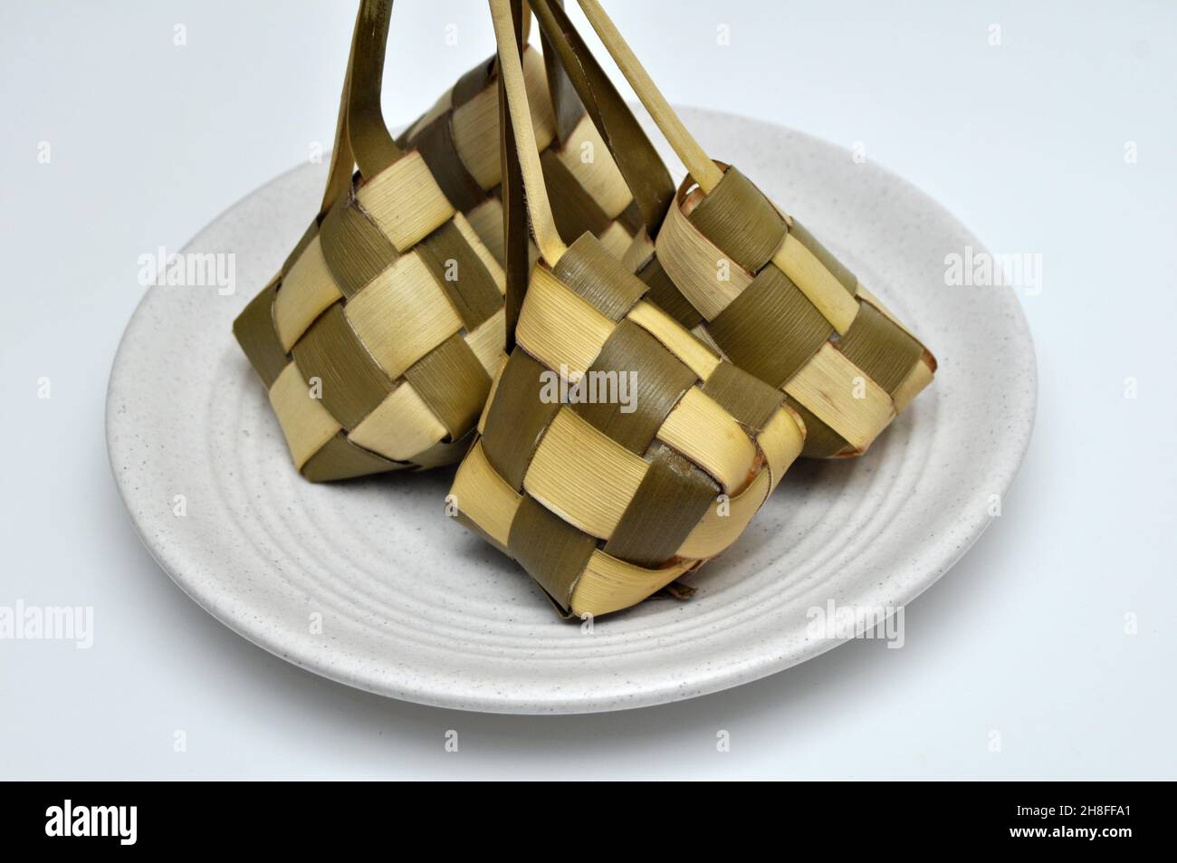 Ketupat is a type of dumpling made from rice packed inside a diamond-shaped container of woven palm leaf pouch. commonly found in Indonesia, Malaysia, Stock Photo