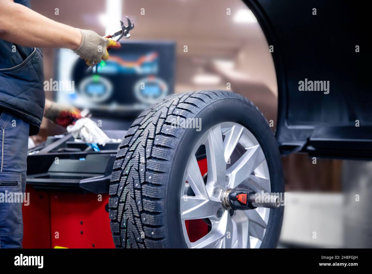 Auto mechanic places weights on steel rim of machine. Concept balancing