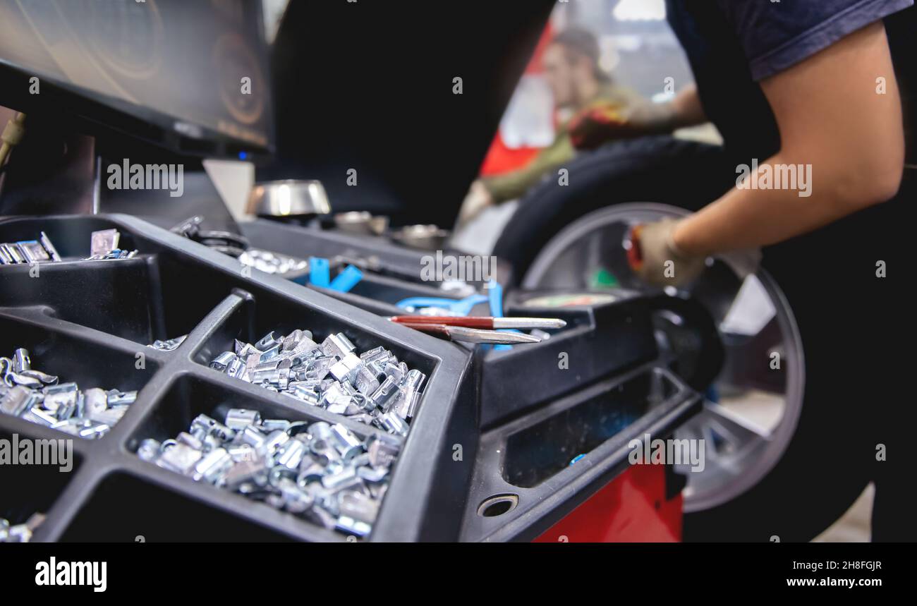 Auto mechanic places weights on steel rim of machine. Concept balancing