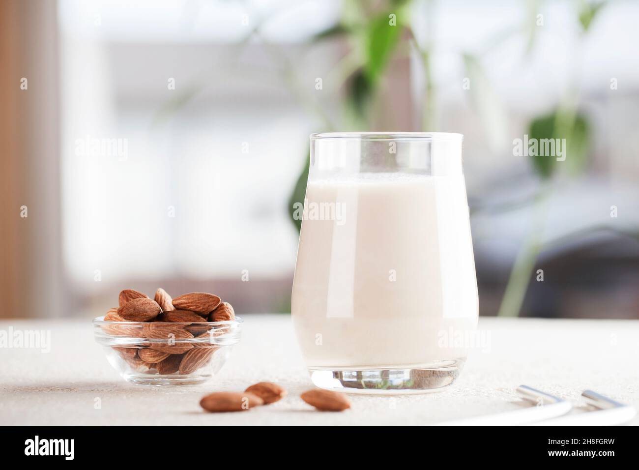 Vegan almond milk in glass with nuts on blurry background. Copy space. Healthy vegetarian food. selective focus. Non dairy alternative milk Stock Photo