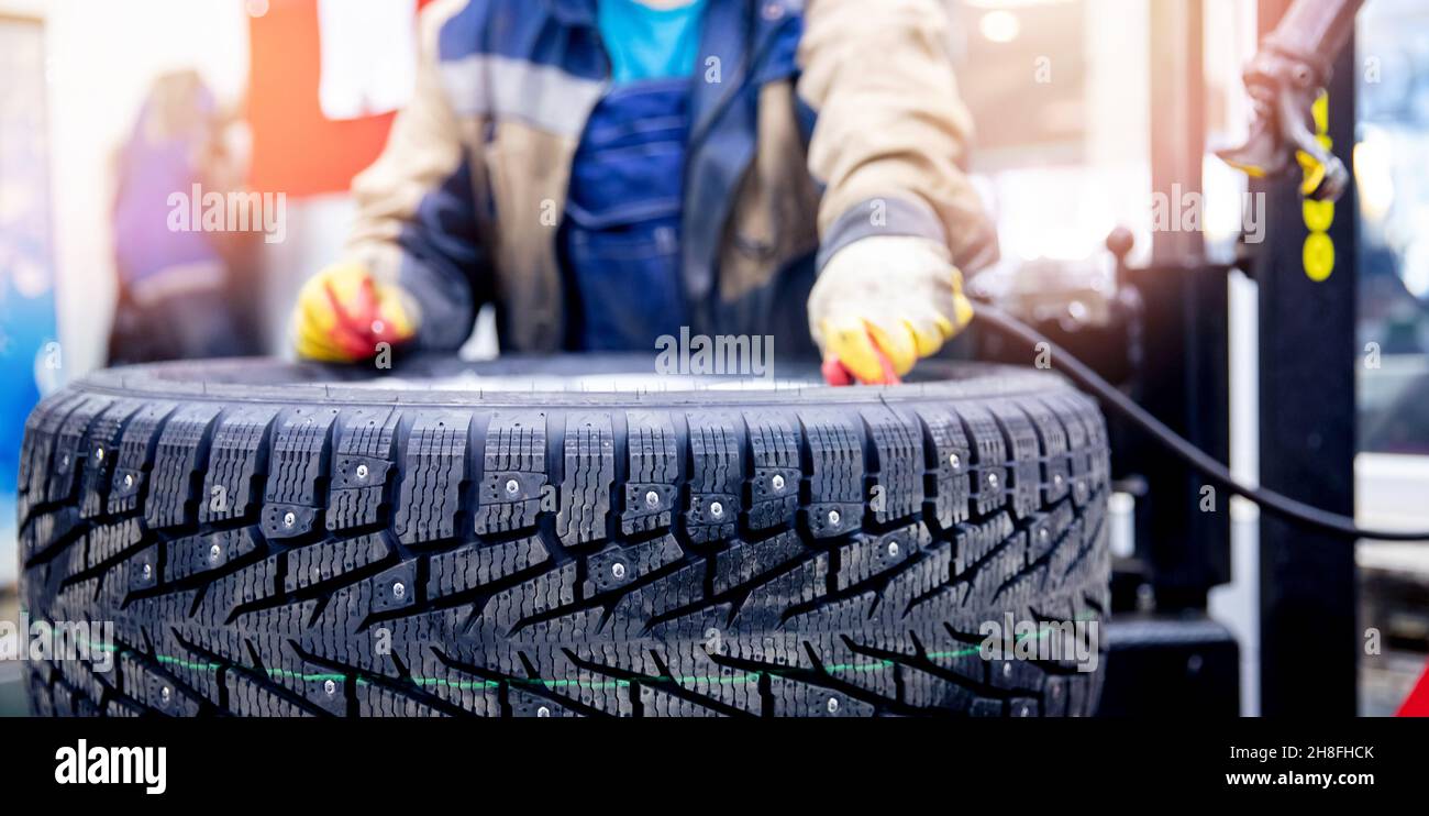 Master mechanic inflates wheel with air at tire fitting station banner photo. Stock Photo