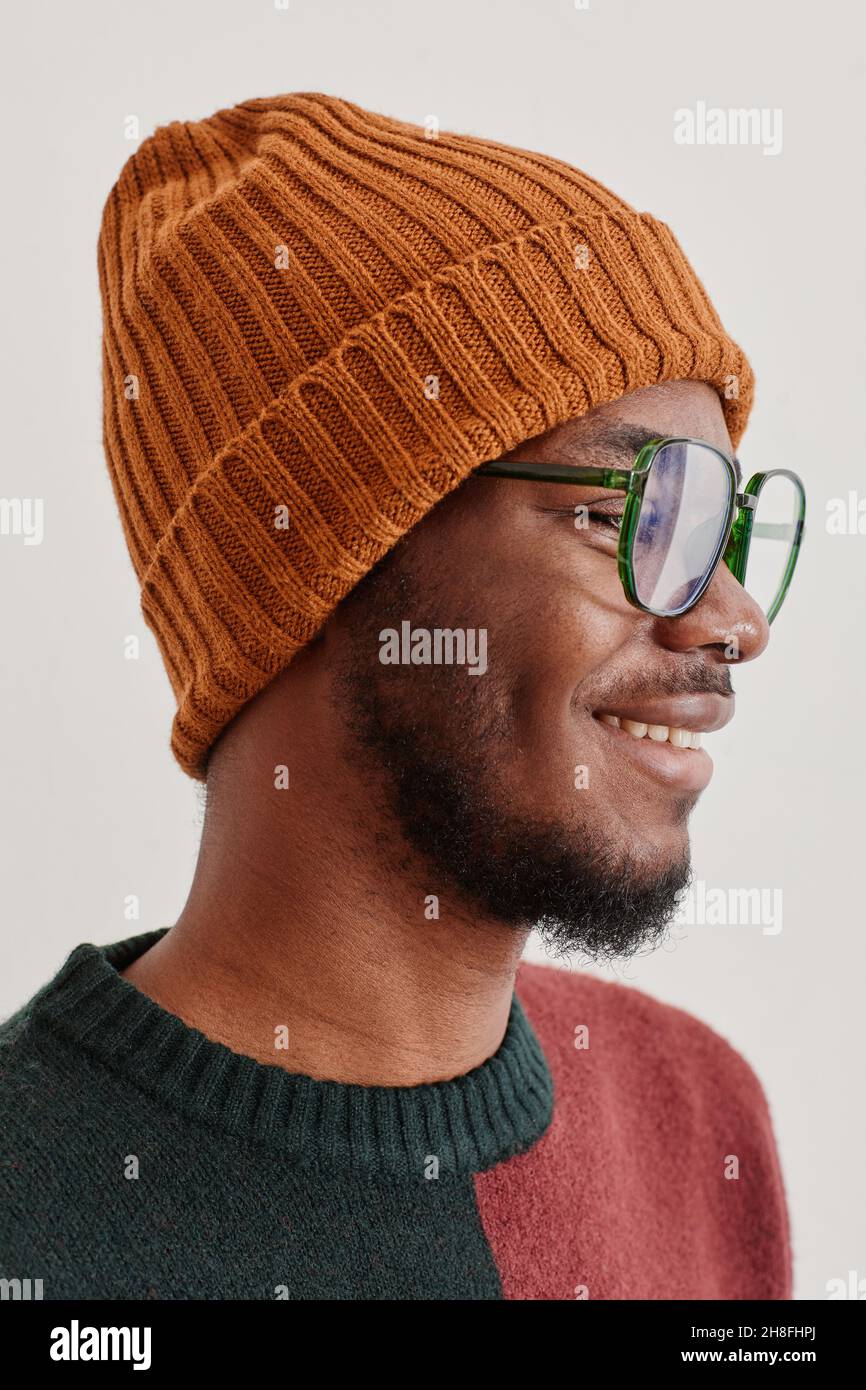 Vertical side view portrait of smiling African-American man wearing knit hat and sweater Stock Photo