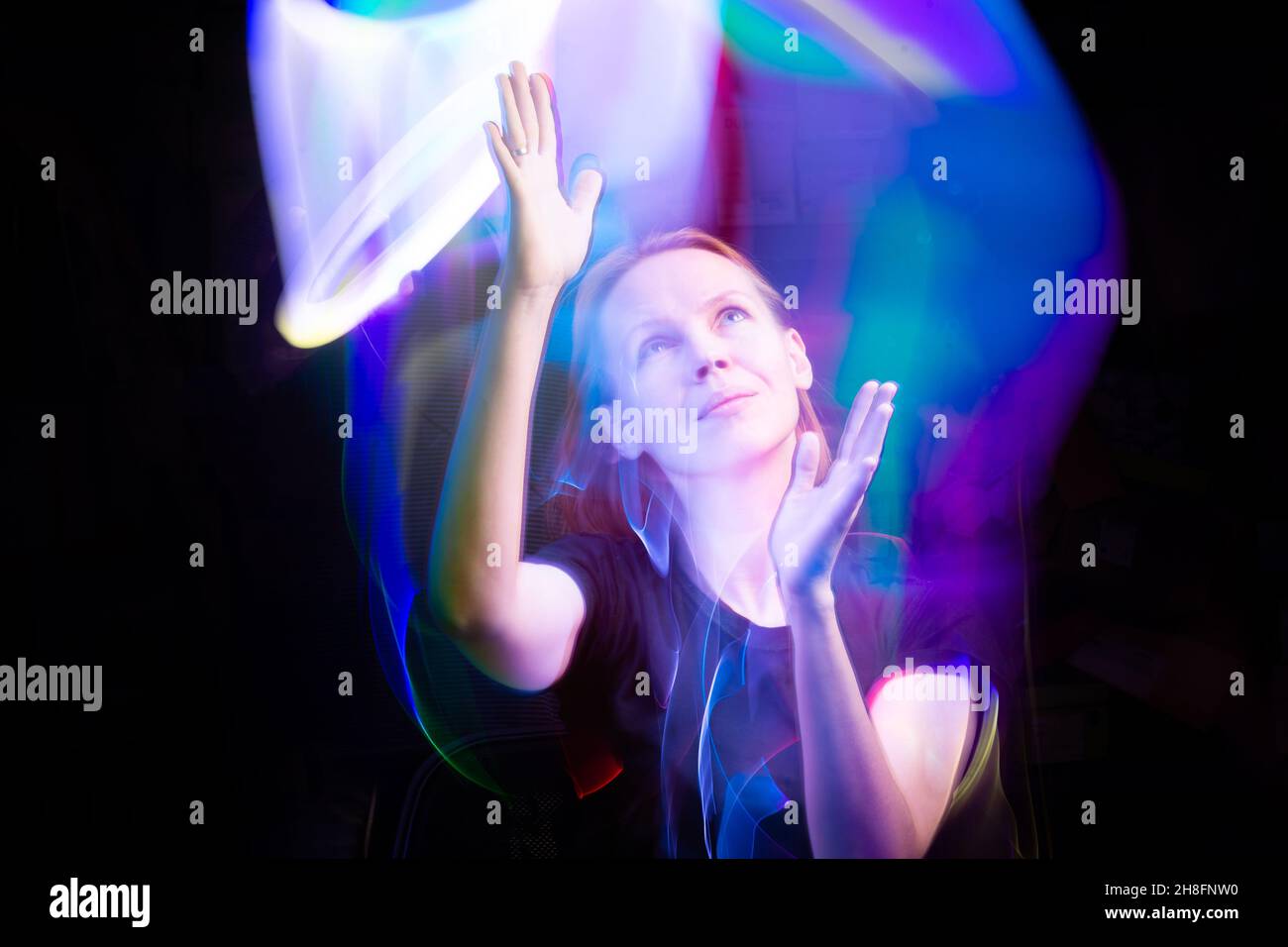 A woman in the dark in a multicolored light. The concept of energy, aura. Stock Photo