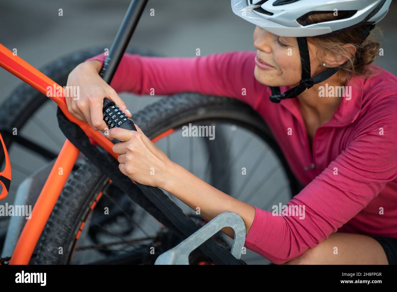 Young woman locking her mountain bike with a numeric lock, setting the