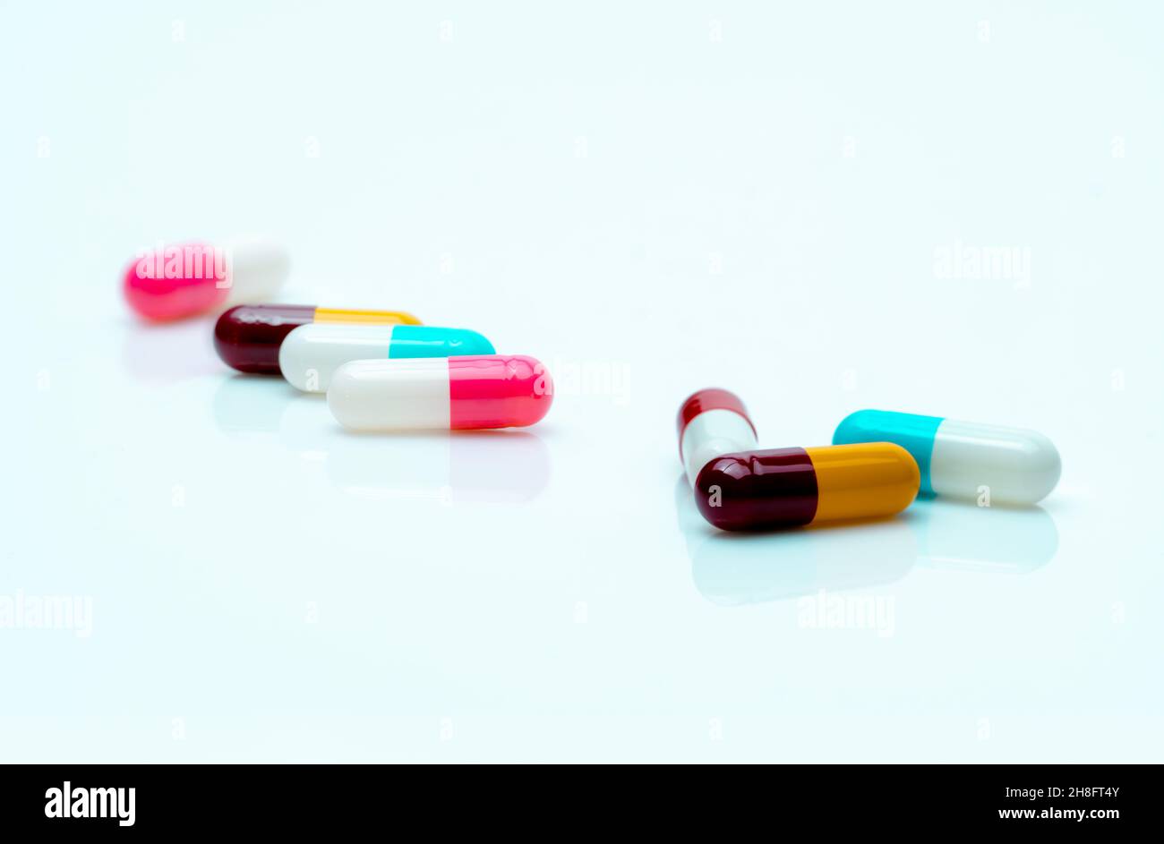 Multi-color pills on white background. Antibiotic capsule pills. Prescription drugs. Pharmaceutical industry. Polypharmacy concept. Capsule. Stock Photo