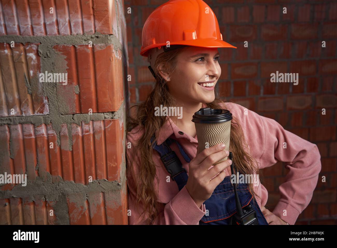 Good-looking woman in builder uniform posing with coffee cup Stock Photo
