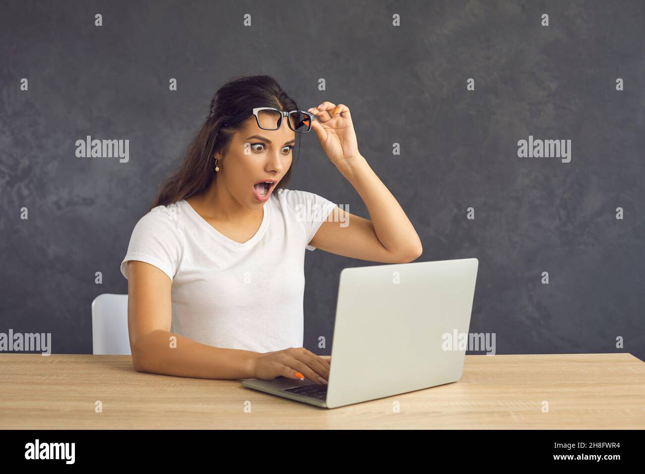 Young woman work on computer shocked by news online Stock Photo