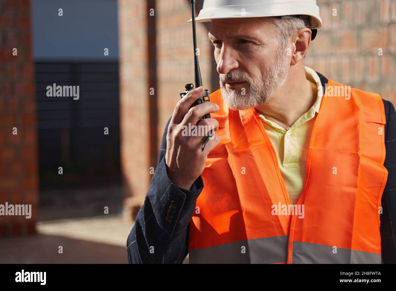 Focused construction expert having a conversation on the radio Stock Photo