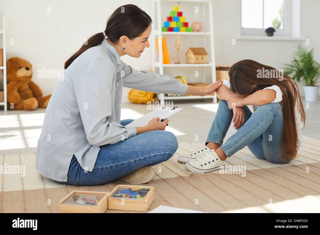 Specialist trying to help sad, stressed child to solve behaviour and learning problems Stock Photo