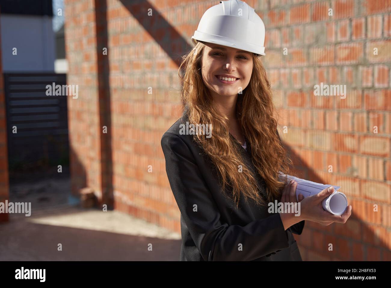 Young ambitious lady posing with a paper roll of whiteprints Stock Photo