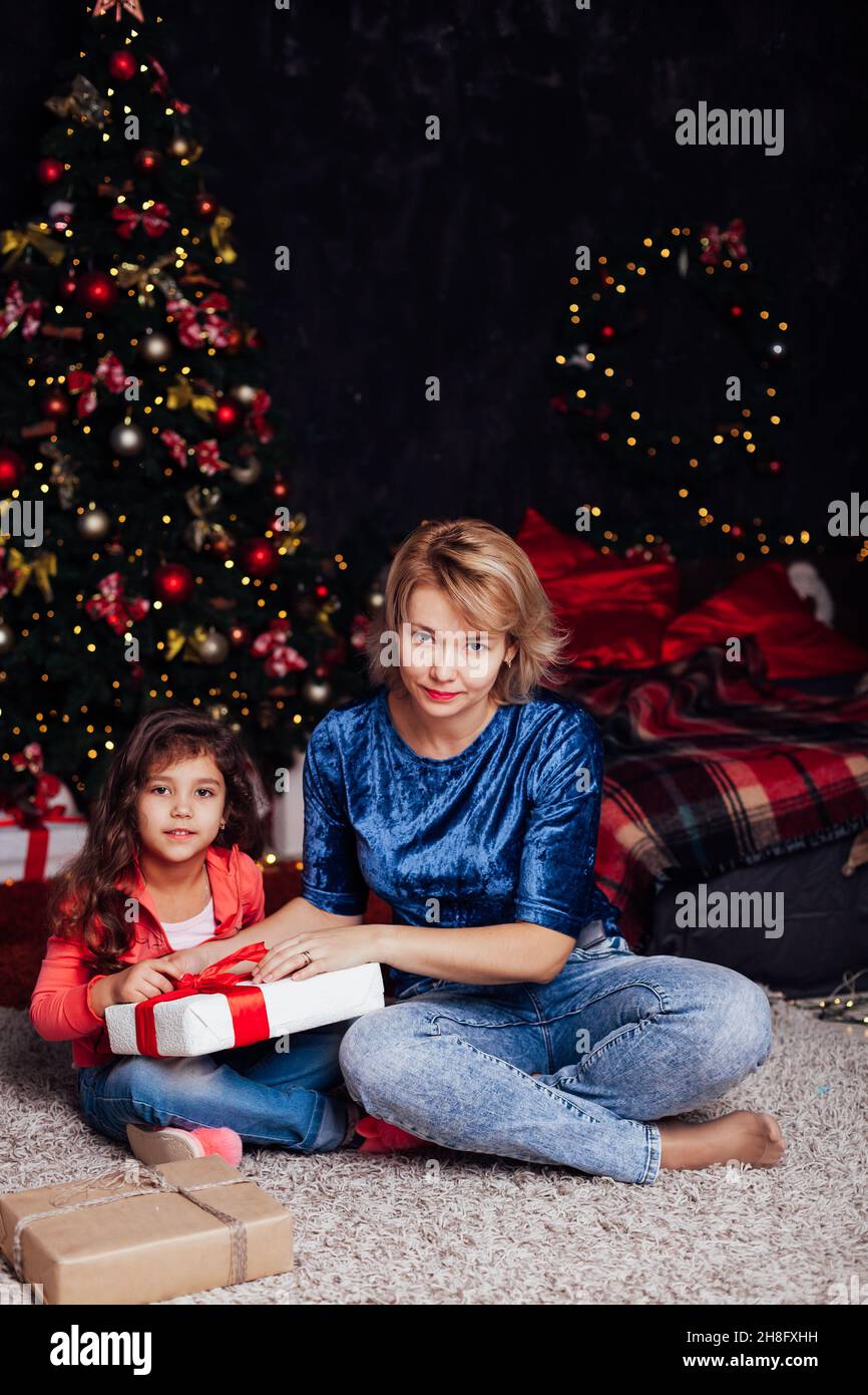 mother and daughter opens gifts at the Christmas tree for the new year