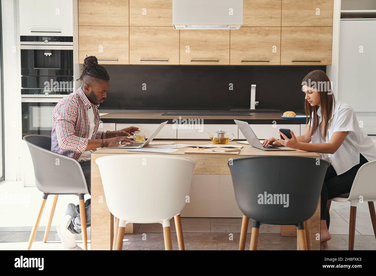 Two concentrated young freelancers sitting at laptops Stock Photo