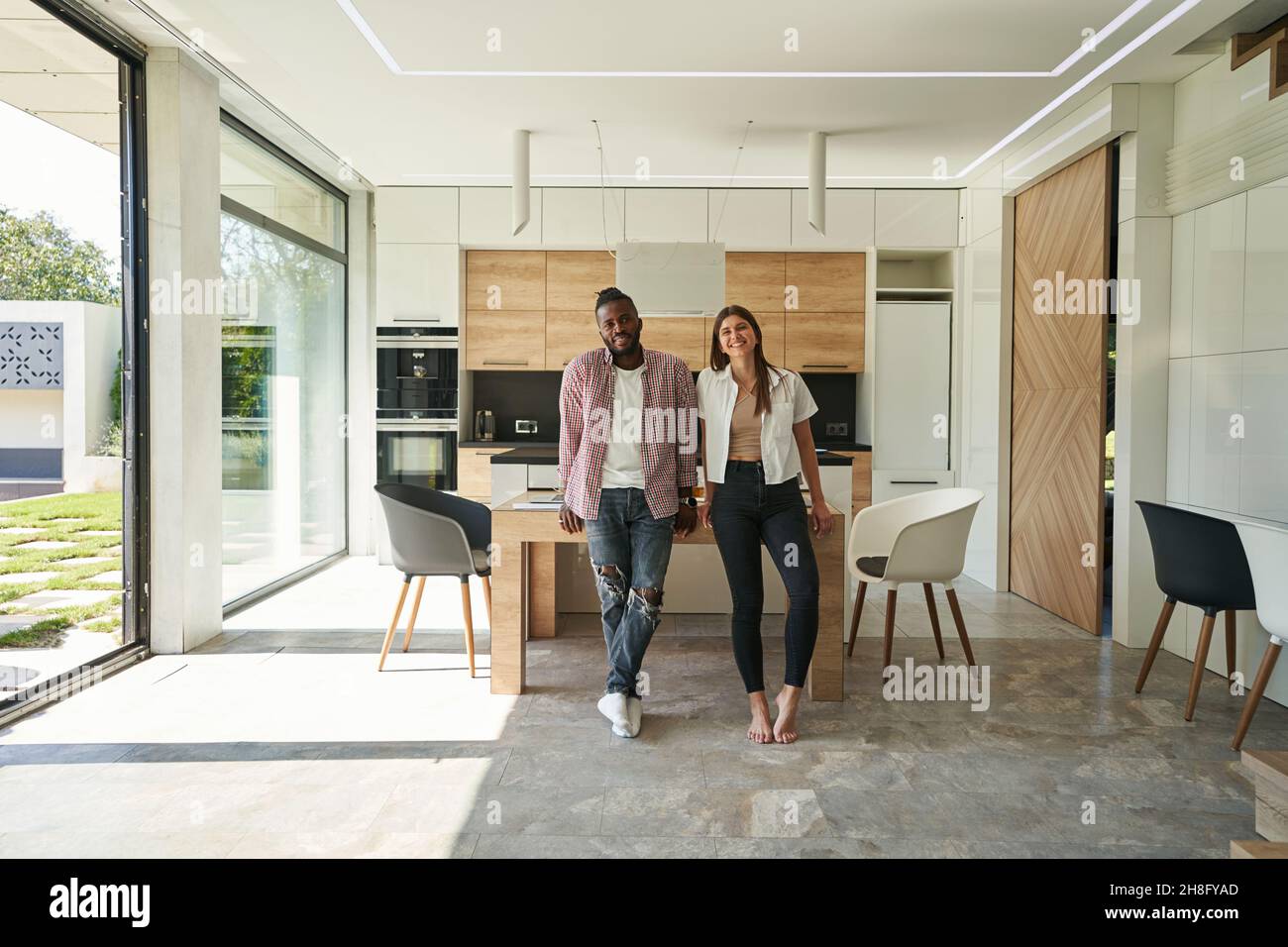 Joyous mixed-race couple posing for camera in kitchen Stock Photo