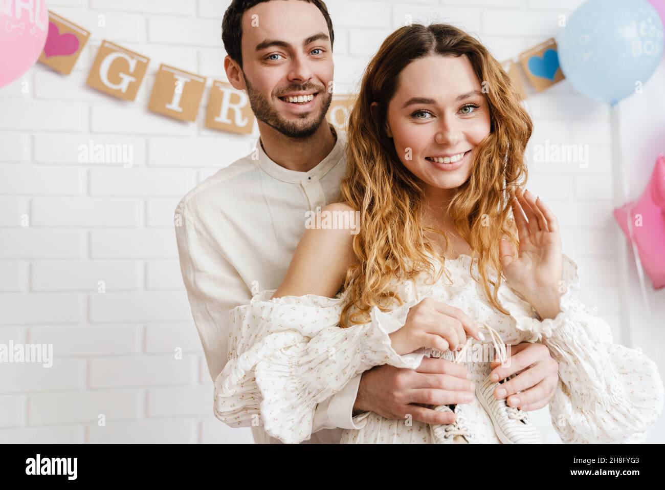 Happy pregnant woman and loving husband hugging tummy standing indoors, celebrating baby shower Stock Photo
