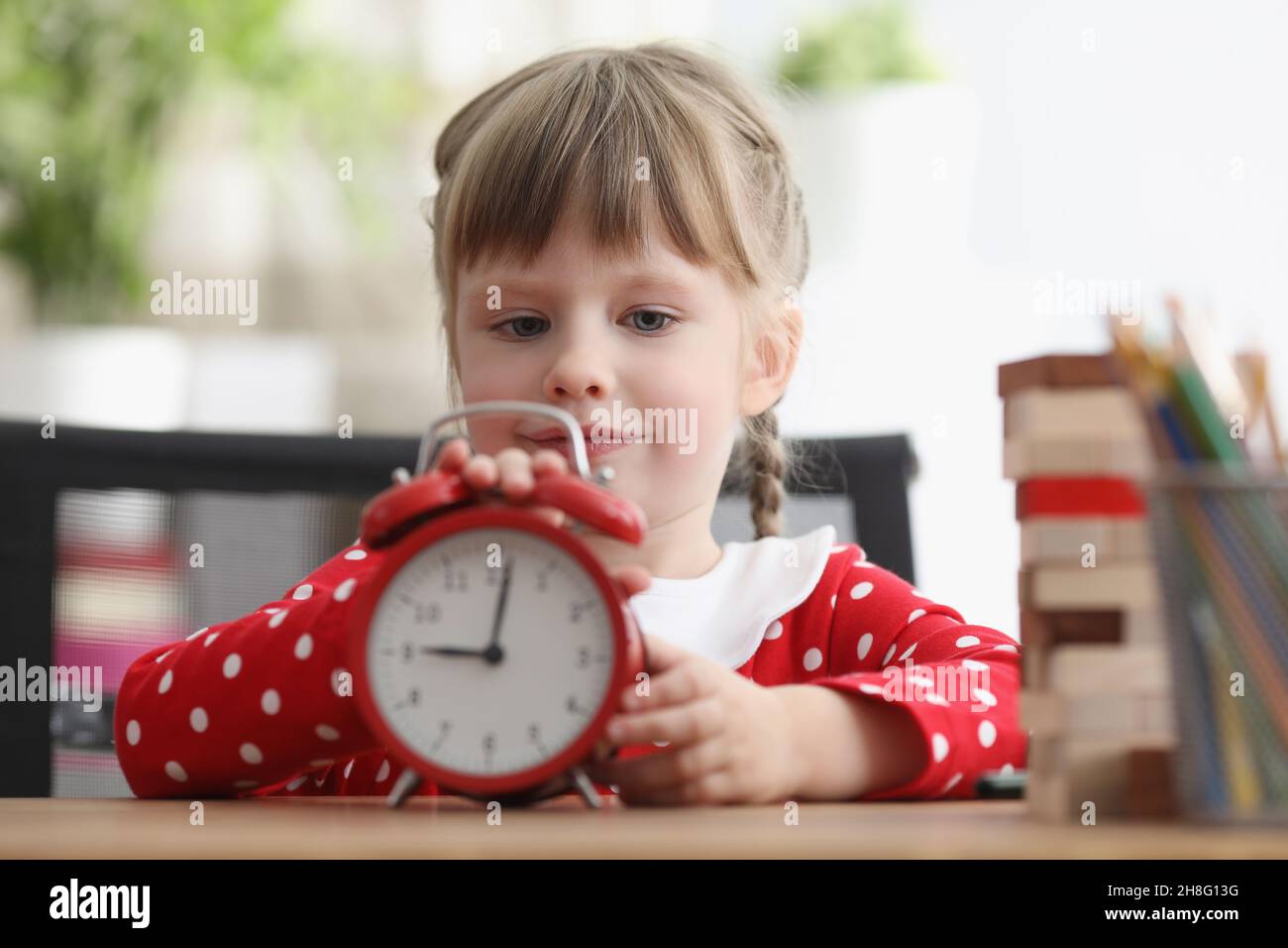 Cute child learn how to understand time and play with red retro clock