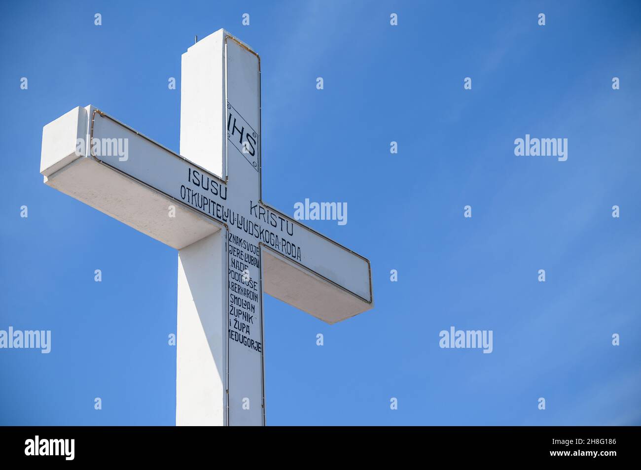 The white Cross on the top of Krizevac (Cross Mountain) in Medjugorje. (Words on the cross read: 'to Jesus Christ, the Redeemer of the human race...') Stock Photo