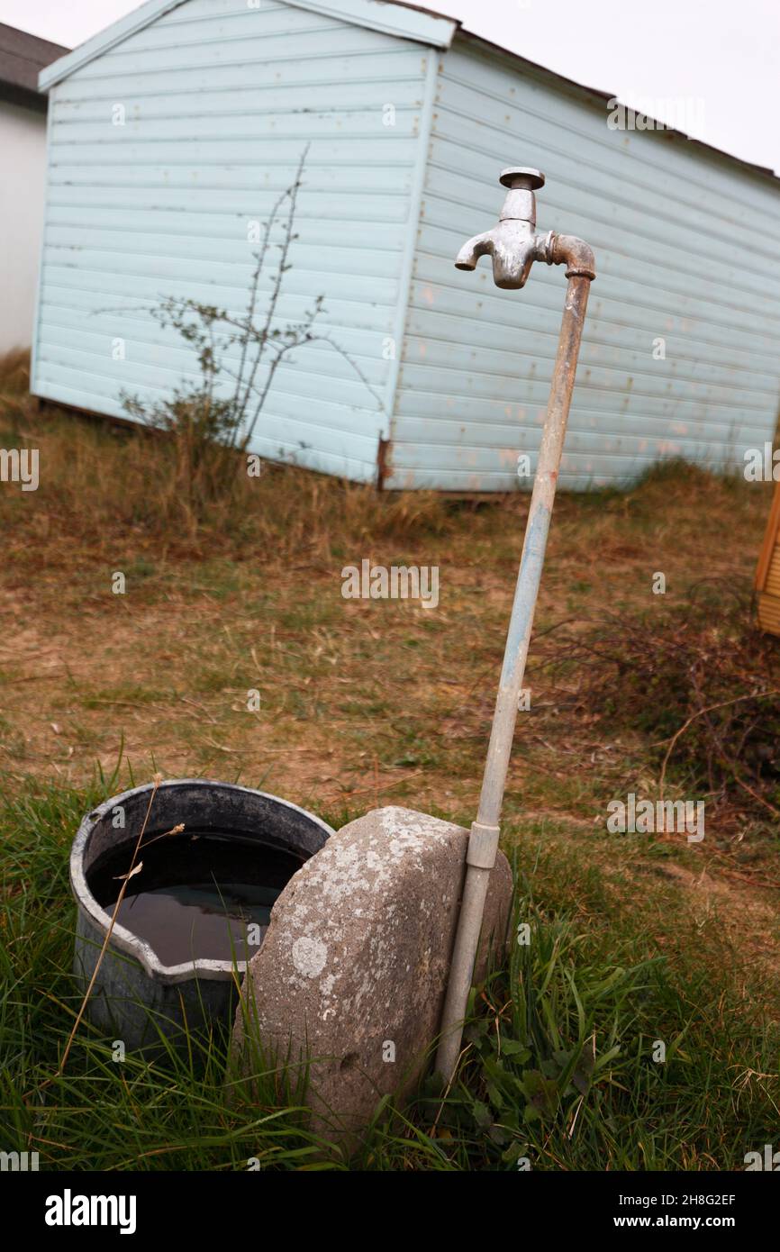 Standpipe and bucket at beach huts. Stock Photo