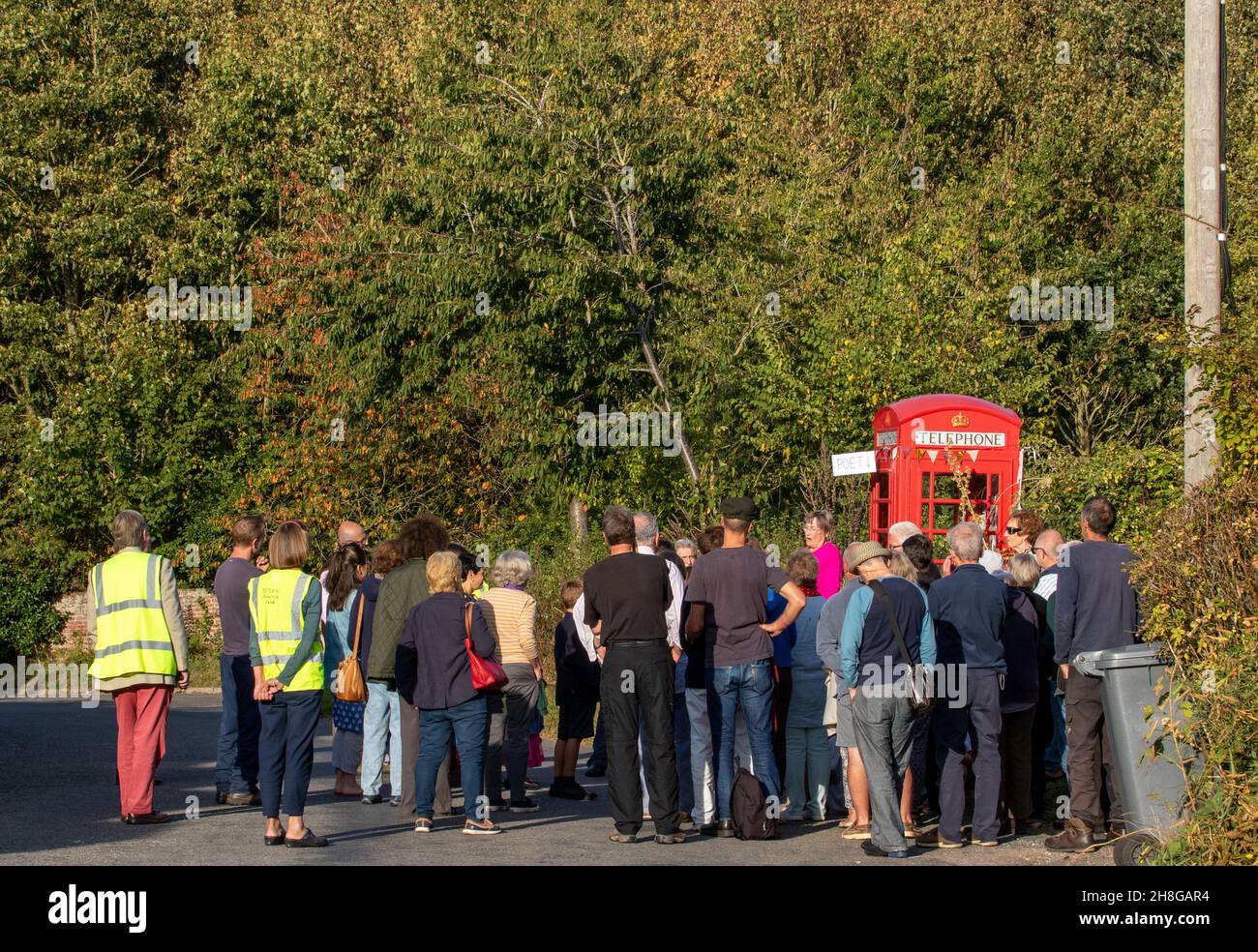 People gathered at a village's red telephone box for a mini poetry festival Stock Photo
