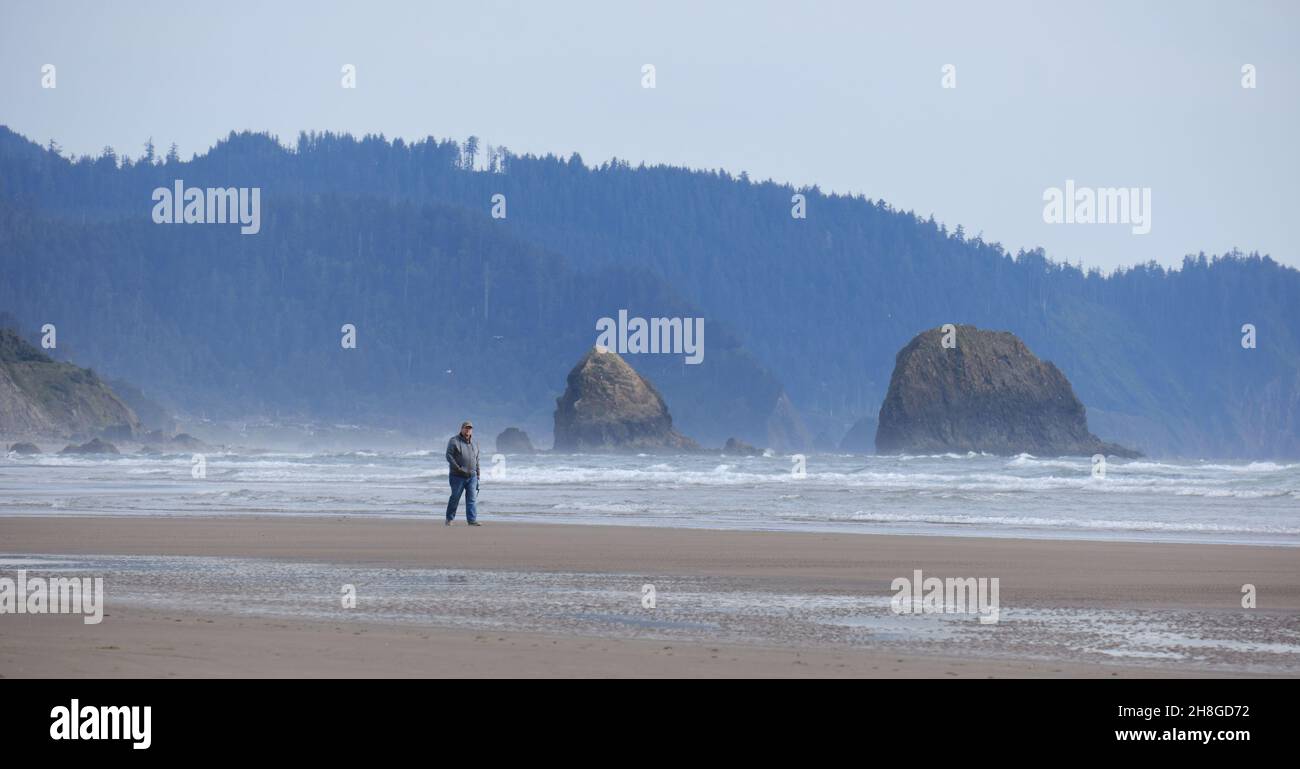 Man walk alone on the beach near Hug Point, Oregon Stock Photo