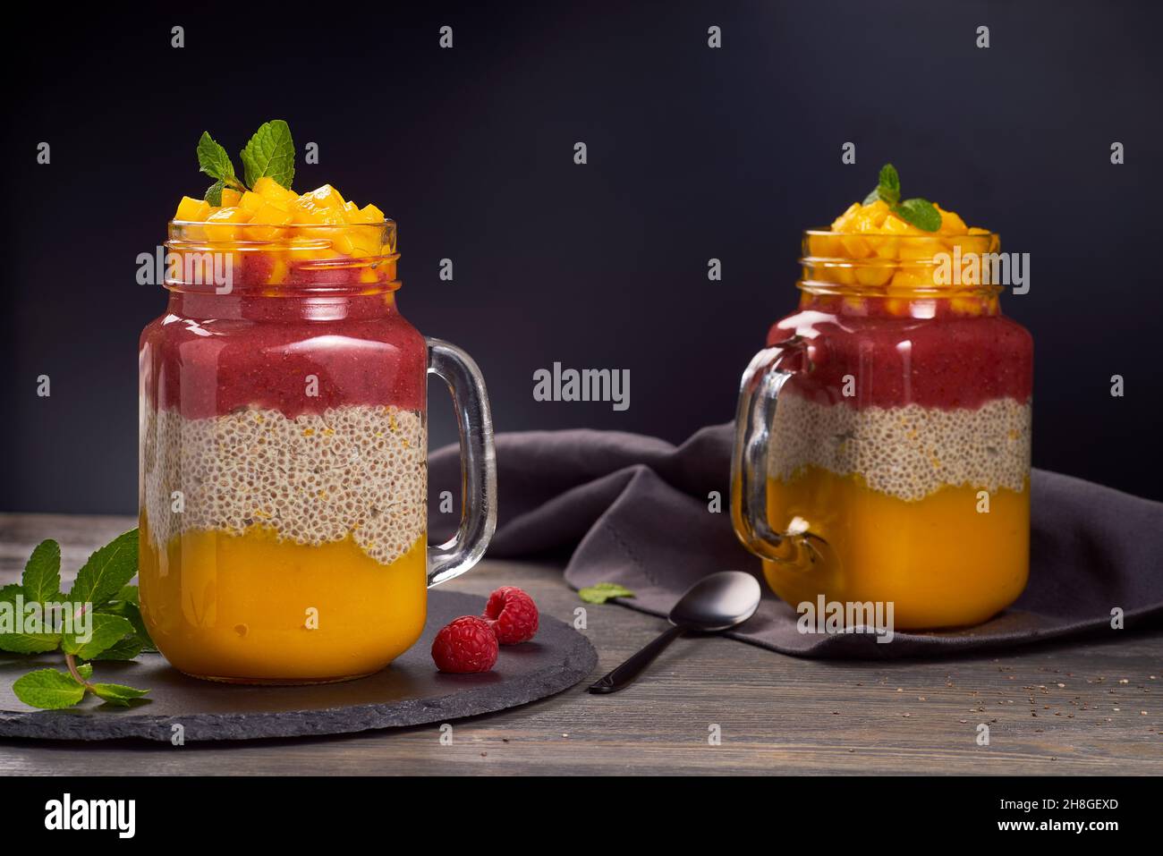 Two jars of layered chia pudding on dark wooden background Stock Photo