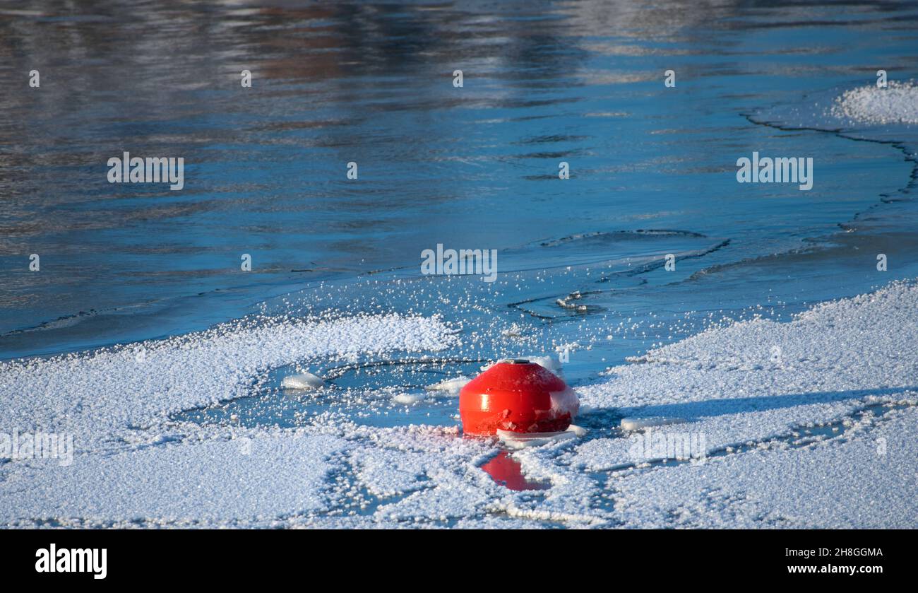 Bright red buoy floating alone in middle of ice and snow in the Baltic Sea in Helsinki, Finland just before complete freeze over of the sea on an extr Stock Photo