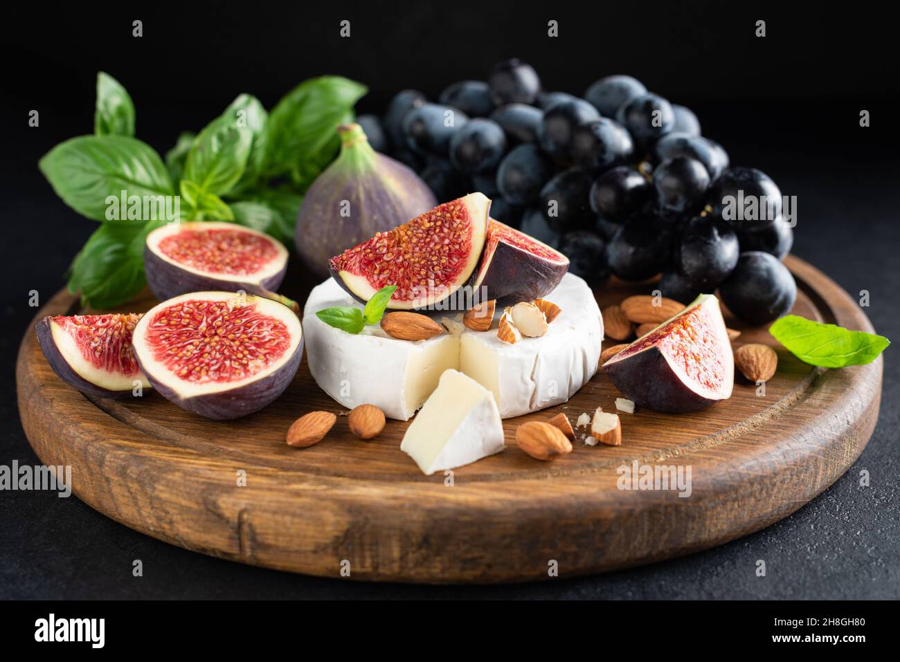 Camembert cheese platter with figs, grapes and nuts. Wooden cheese board Stock Photo