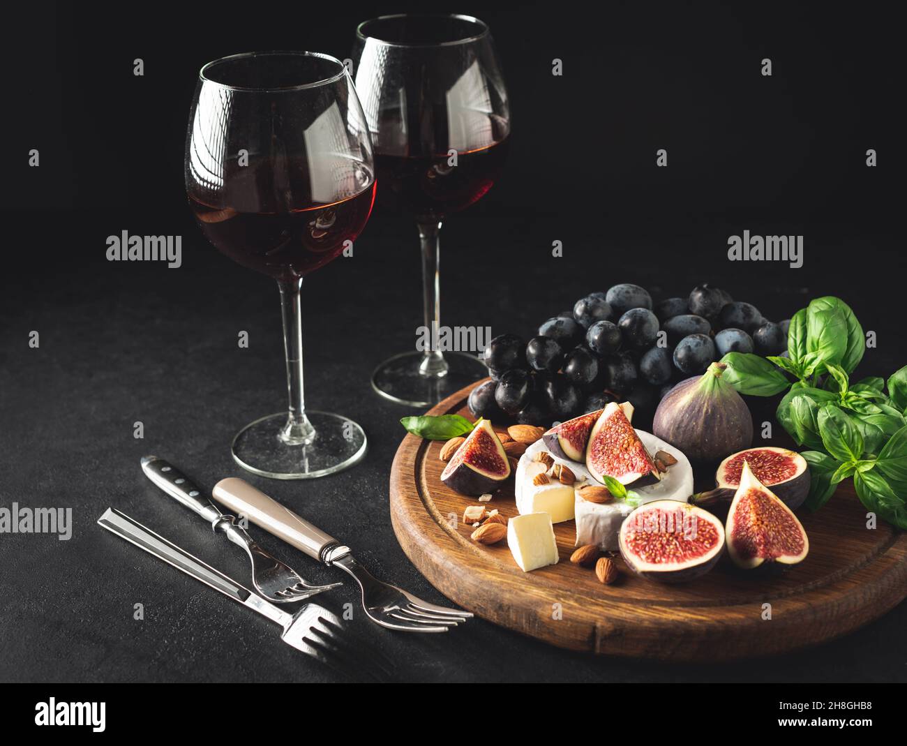 Gourmet wine and cheese appetizer set with camembert and figs. Dark toned image, copy space. Still life Stock Photo