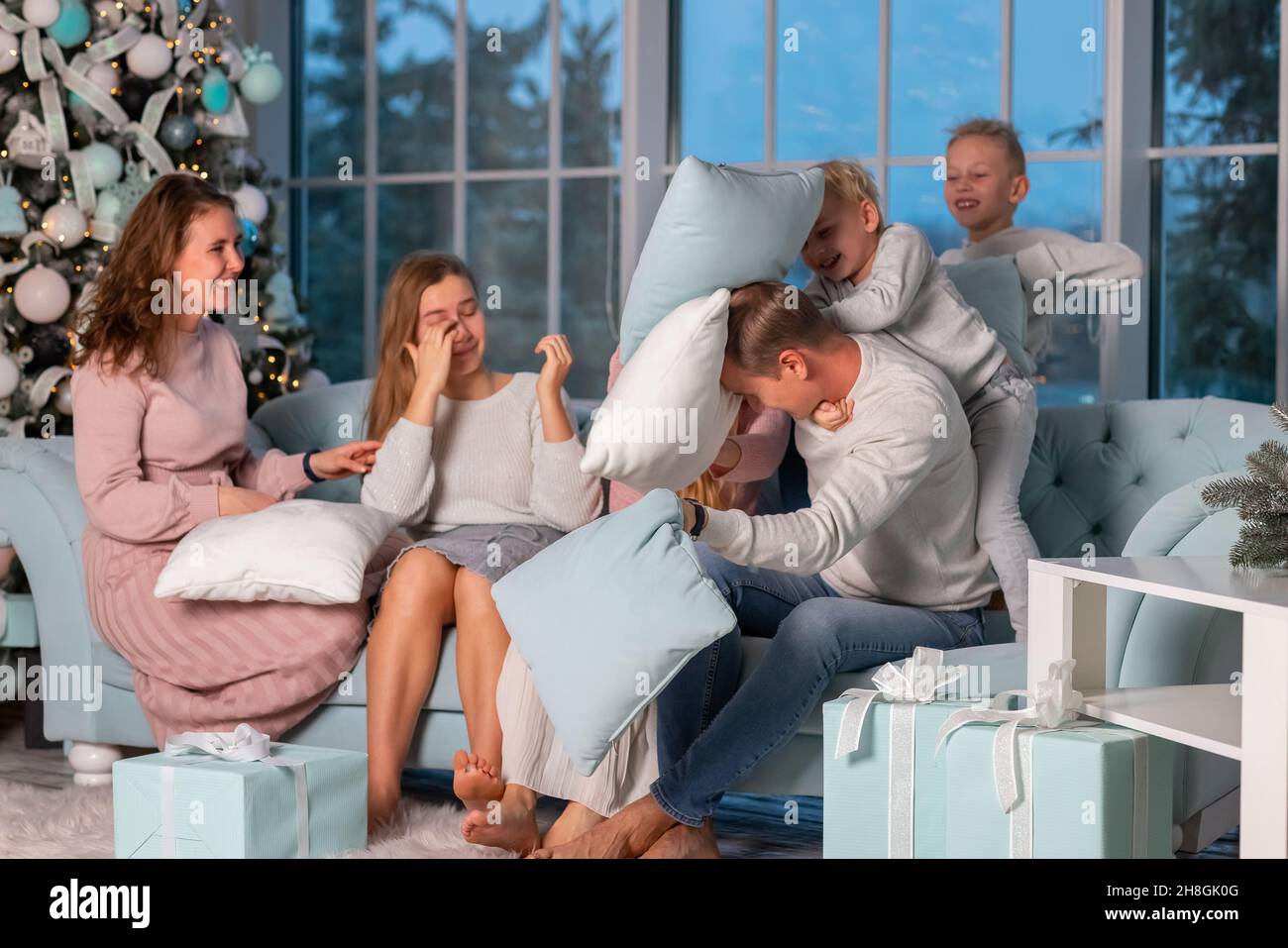 Big Happy family with many kids having fun and pillow fight under the Christmas tree. Christmas family eve, christmas mood concept Stock Photo