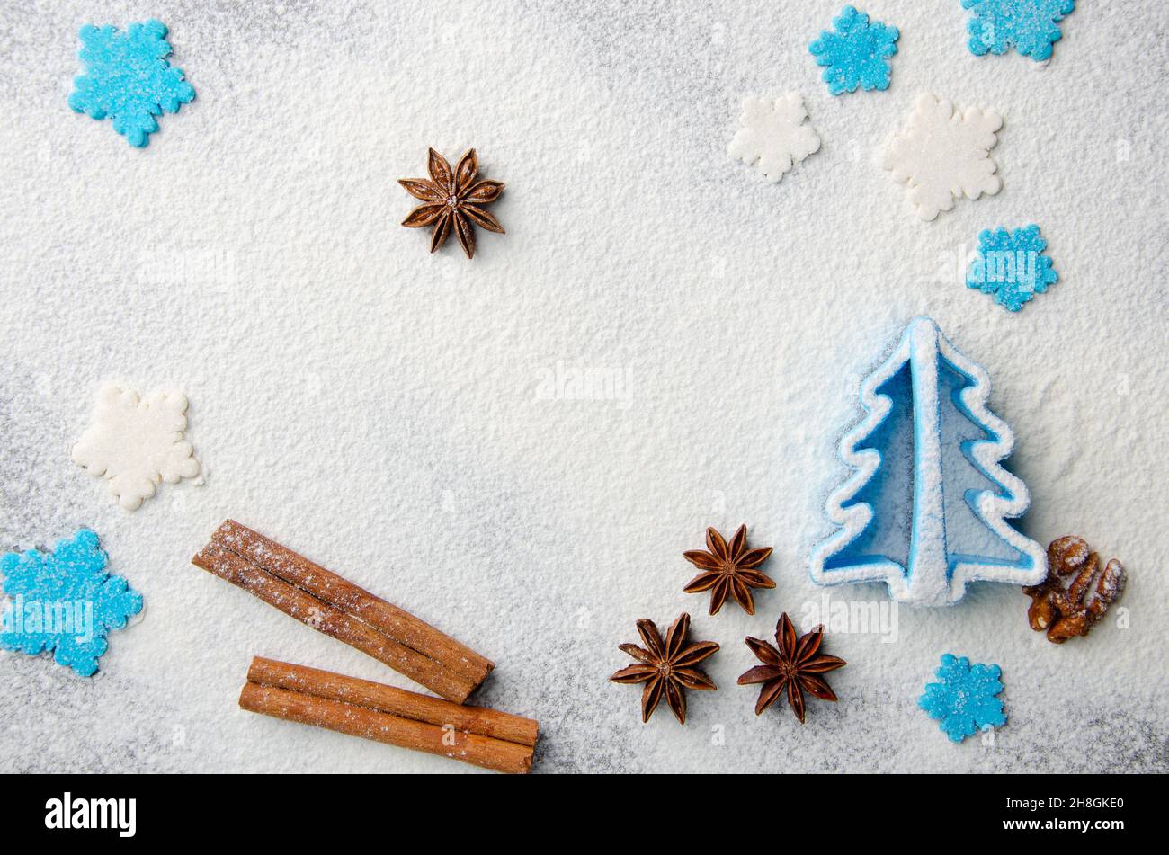 Christmas kitchen background made of flour, cinnamon sticks, anise,  cookie cutter and sugar sprinkles Stock Photo