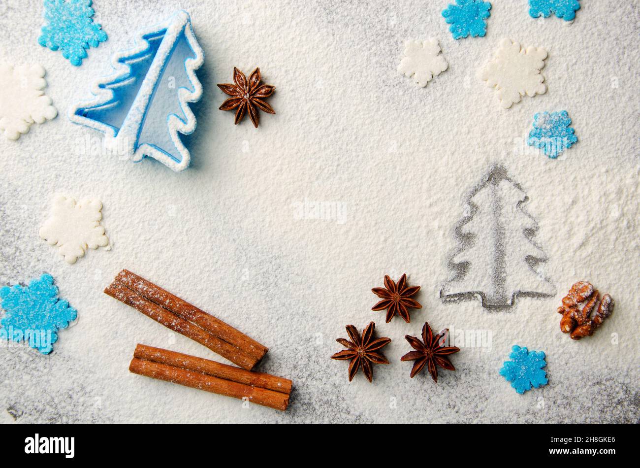 Christmas kitchen background made of flour, cinnamon sticks, anise,  cookie cutter and sugar sprinkles Stock Photo