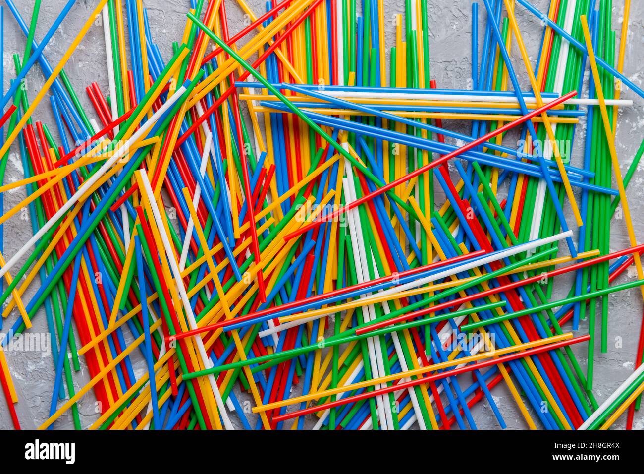 many multi-colored plastic tubes for cocktail on Colored background, top view. Stock Photo
