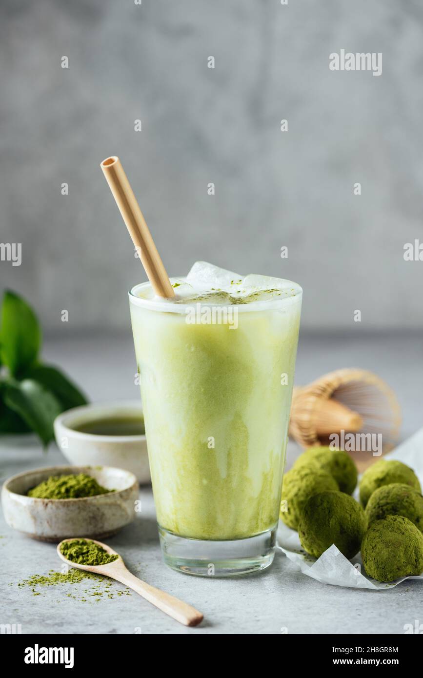Matcha ice latte healthy vegan drink in glass served with matcha energy balls. Grey background copy space for text or design Stock Photo