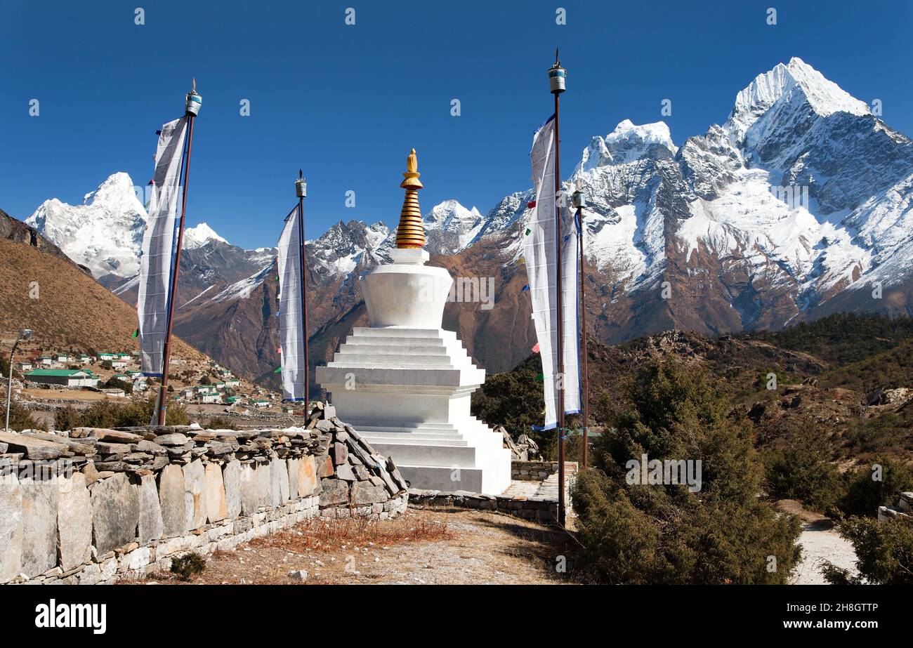 White stupa, prayer flags, mani wall with buddhist prayer symbols - mounts Kangtega, Thamserku and Ama Dablam, way to Everest base camp, Khumbu valley Stock Photo