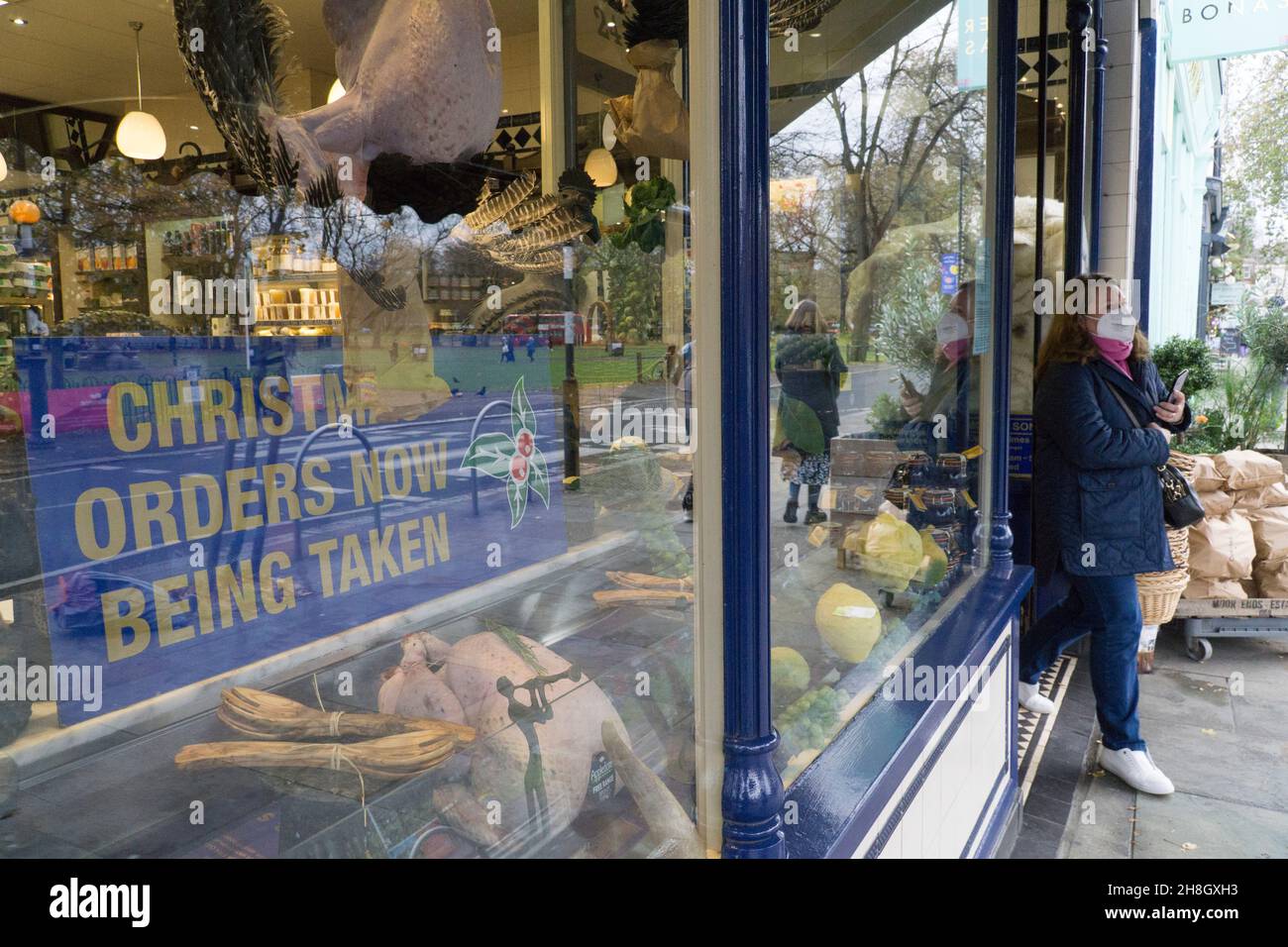 London, UK, 30 November 2021: In Clapham shoppers are now obliged by law to wear a face mask in shops or on public transport. At the upmarket butchers M. Moen & Son, opposite Clapham Common, a festive display announces they are taking orders for Christmas. Anna Watson/Alamy Live News Stock Photo