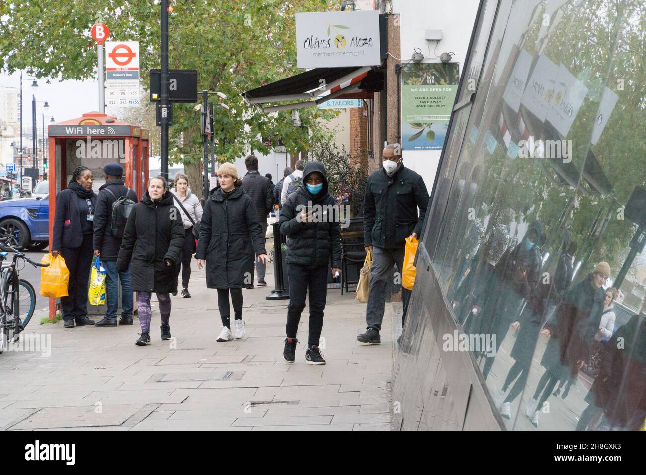 London, UK, 30 November 2021: Shoppers are now obliged by law to wear a face mask in shops or on public transport. At the Clapham High Street branch of Sainsbury's supermarket, shoppers come and go, often removing their masks as soon as they step into the fresh air outside. Anna Watson/Alamy Live News Stock Photo