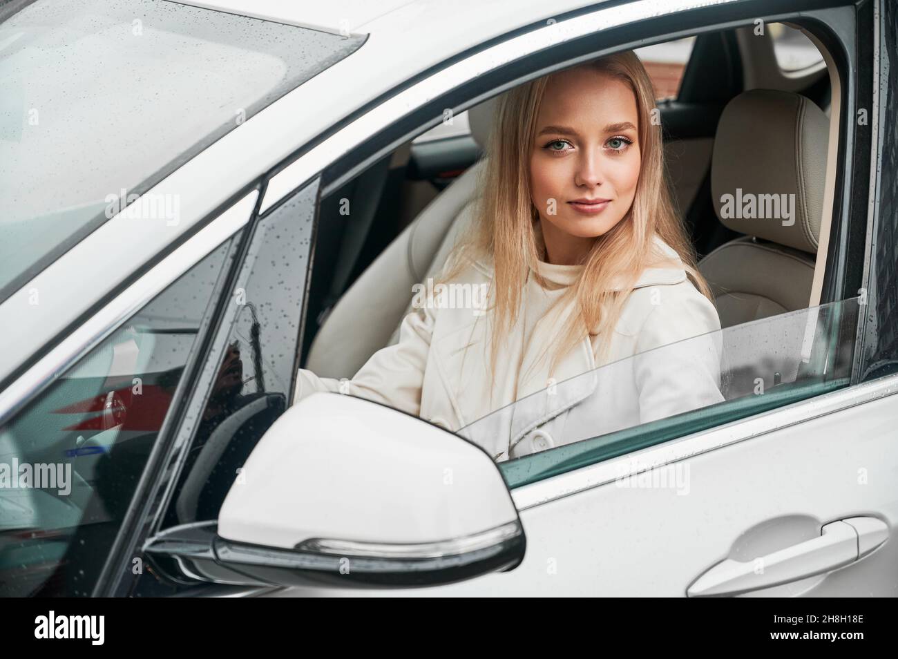 Beautiful young woman driving modern car. Female driver sitting in the car and looking to the camera. Stock Photo