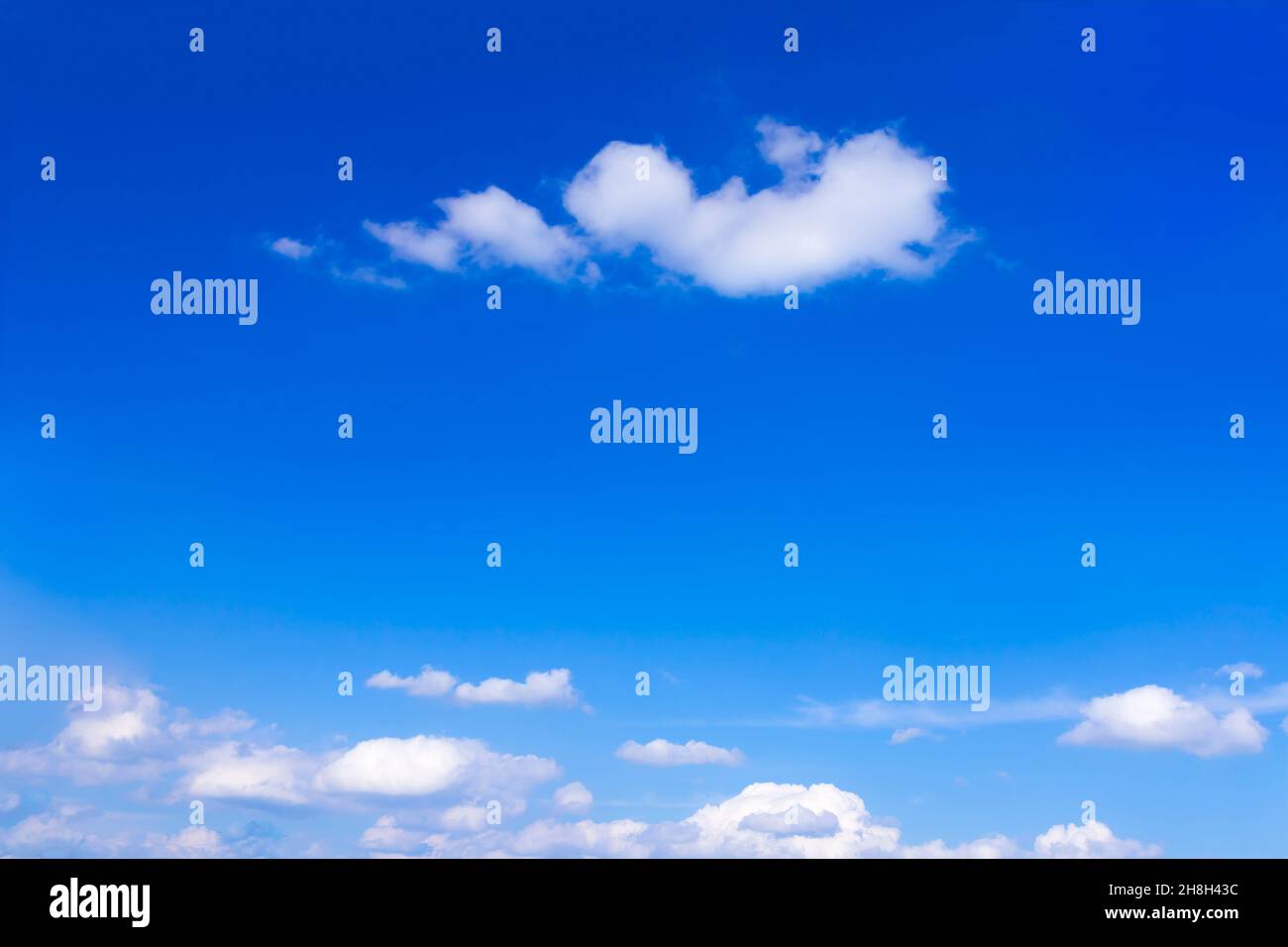 Bright blue summer sky with a few fluffy white clouds, background texture, copy or text space. Stock Photo