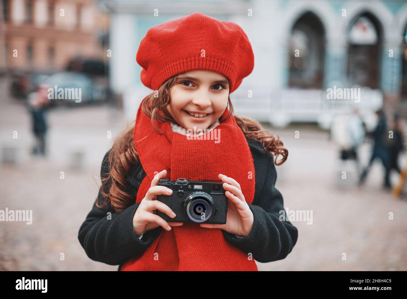 beautiful girl in a red beret and scarf takes pictures on the city ...